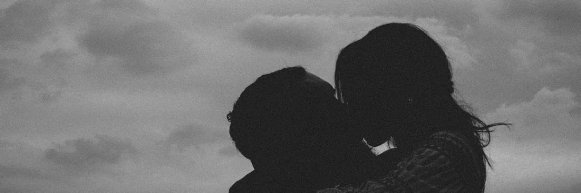 a couple of people standing next to each other under a cloudy sky