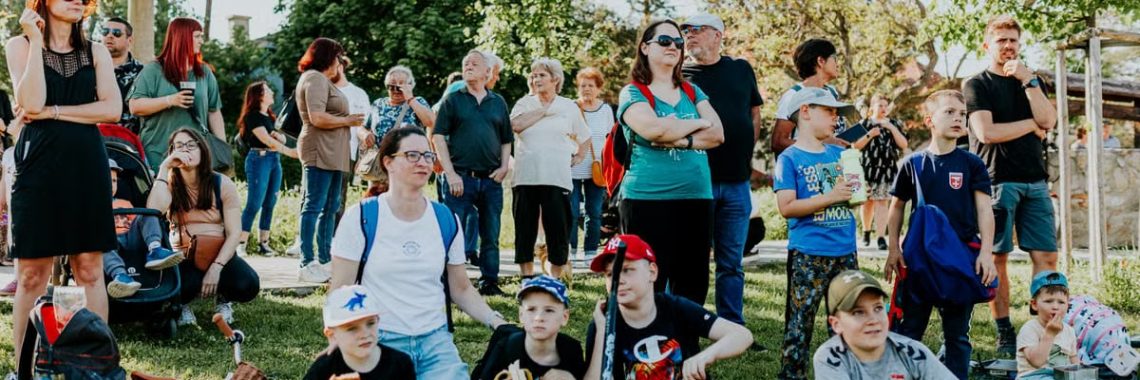 A diverse group of people enjoying a sunny day at an outdoor community event in a park setting.
